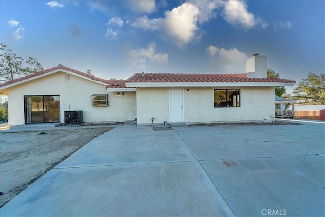 back of house with a tile roof, a patio, a chimney, stucco siding, and cooling unit