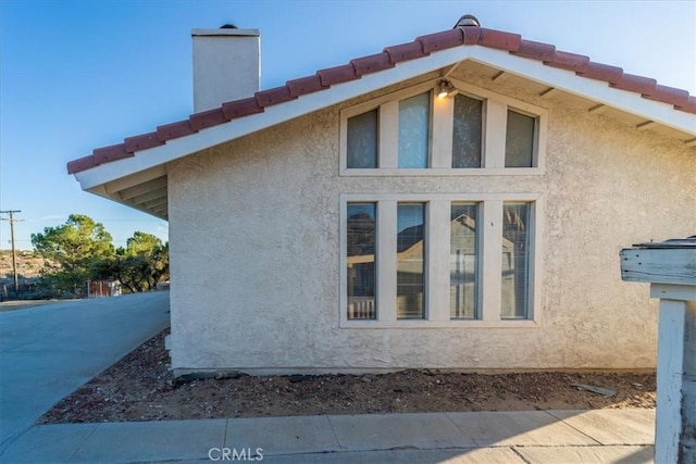 view of side of home with a chimney and stucco siding