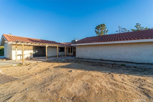 view of front of home with a patio area, a tiled roof, and stucco siding