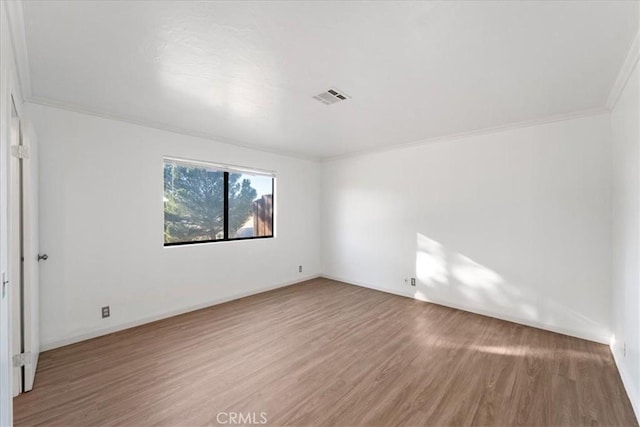 spare room featuring visible vents, wood finished floors, and ornamental molding