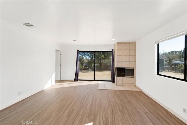 unfurnished living room featuring visible vents, a fireplace, light wood-style flooring, and baseboards