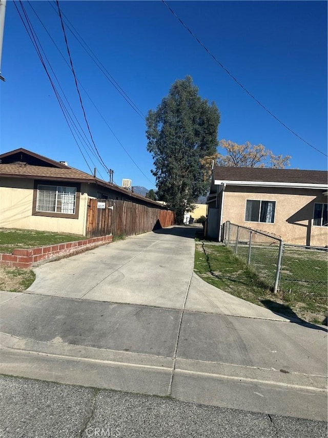 view of property exterior with concrete driveway and fence