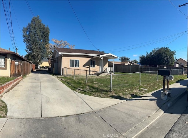 view of property exterior featuring a yard, concrete driveway, fence private yard, and stucco siding