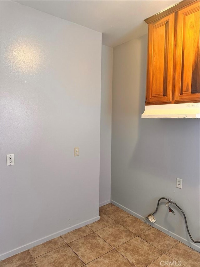 laundry room with light tile patterned floors, cabinet space, and baseboards