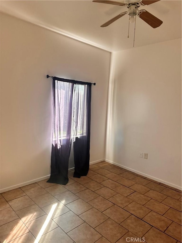 empty room with ceiling fan, tile patterned floors, and baseboards