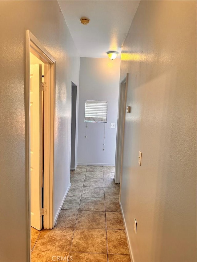 hallway featuring baseboards and light tile patterned flooring