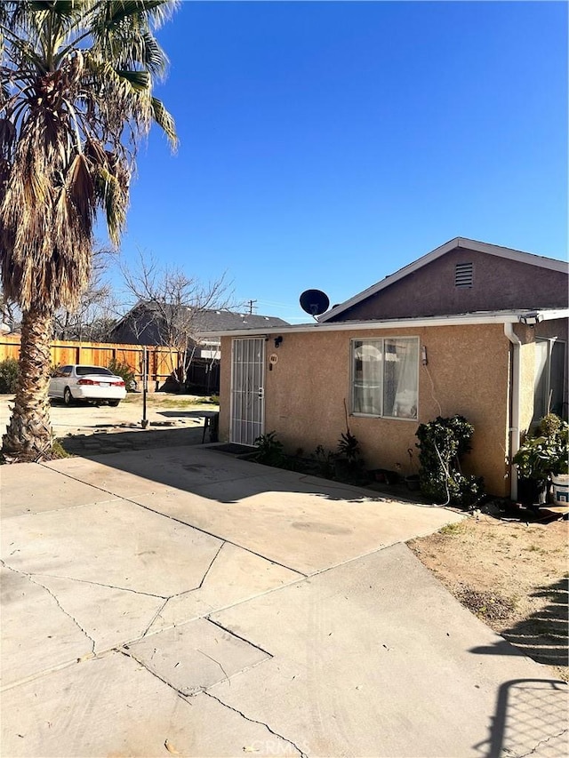 view of front of house with concrete driveway, a patio, fence, and stucco siding