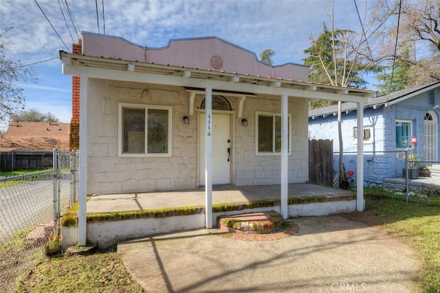 view of front facade with fence private yard, concrete block siding, and metal roof