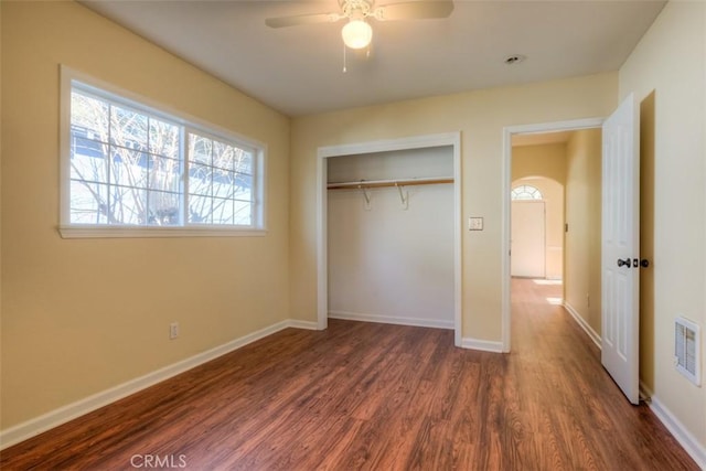 unfurnished bedroom with baseboards, visible vents, a ceiling fan, dark wood-type flooring, and a closet