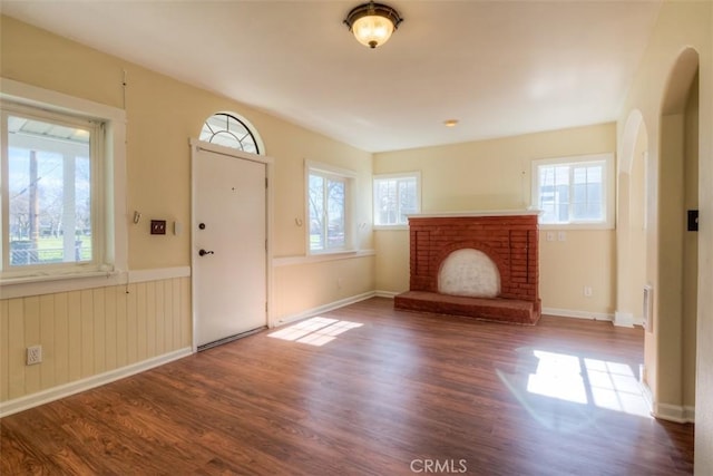 entryway with dark wood-style floors, a fireplace, and plenty of natural light