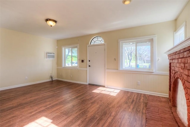 foyer entrance featuring a fireplace, wainscoting, dark wood finished floors, and a wealth of natural light