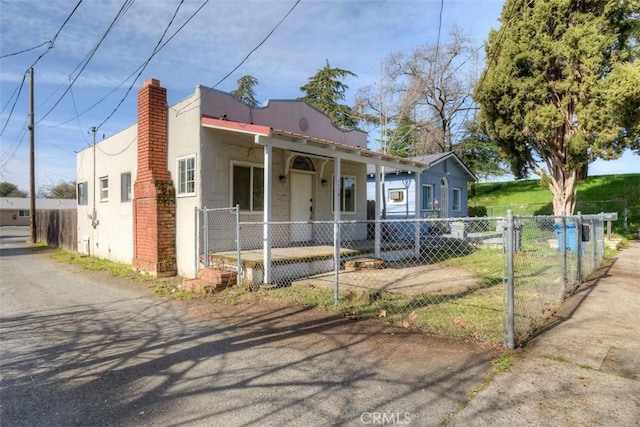 view of front facade featuring a fenced front yard, a chimney, and stucco siding