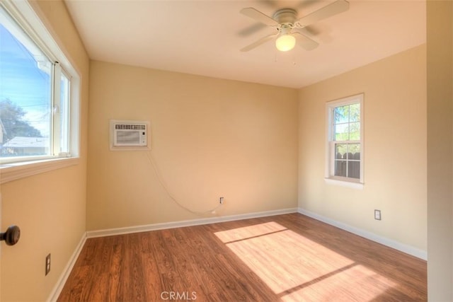 empty room with a ceiling fan, a wall mounted air conditioner, baseboards, and wood finished floors