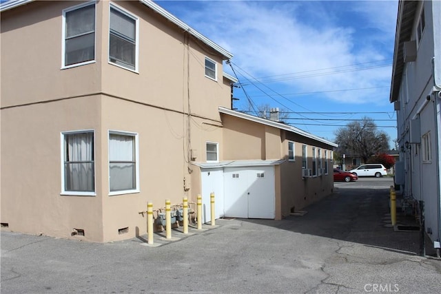 view of side of property with crawl space and stucco siding