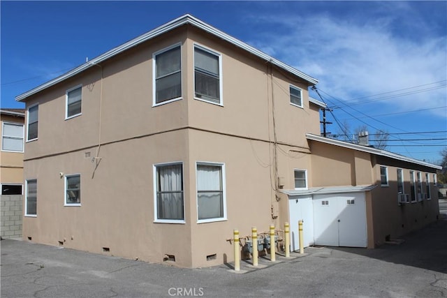 view of side of property with cooling unit, crawl space, and stucco siding