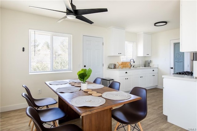 dining room featuring light wood-type flooring, ceiling fan, and baseboards