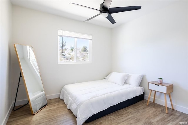 bedroom with ceiling fan, light wood finished floors, and baseboards