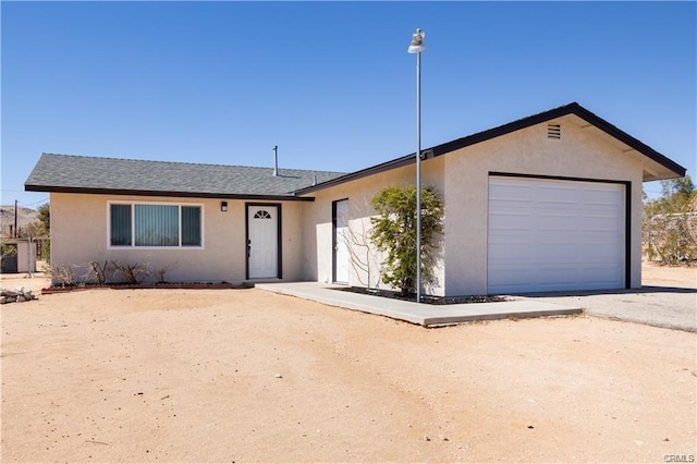 single story home featuring aphalt driveway, an attached garage, a shingled roof, and stucco siding