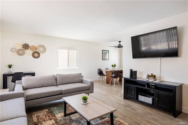 living room featuring ceiling fan, baseboards, and wood finished floors