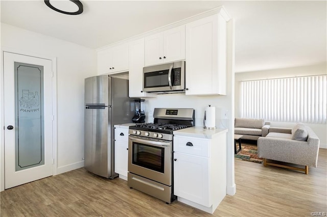 kitchen featuring light countertops, appliances with stainless steel finishes, light wood-style floors, and white cabinets