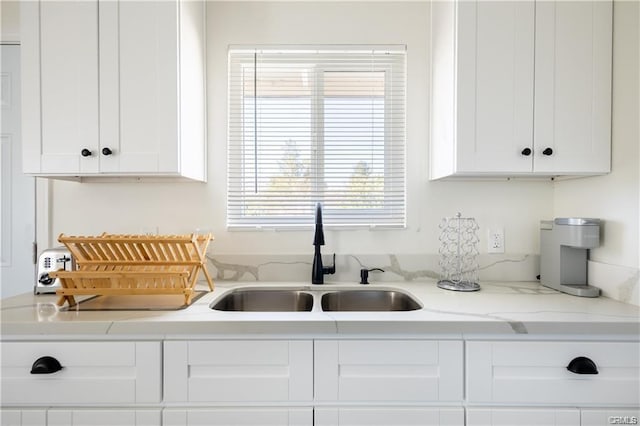 kitchen featuring white cabinets, a sink, and light stone countertops