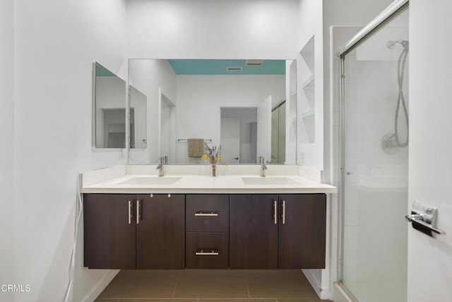 full bath featuring double vanity, a shower stall, and a sink