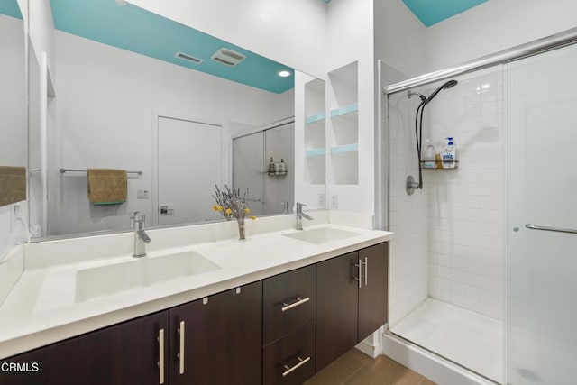 bathroom with visible vents, a sink, a shower stall, and double vanity