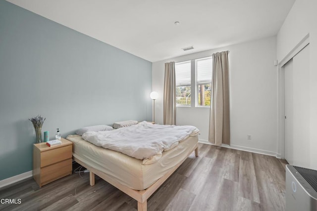 bedroom featuring wood finished floors, visible vents, and baseboards