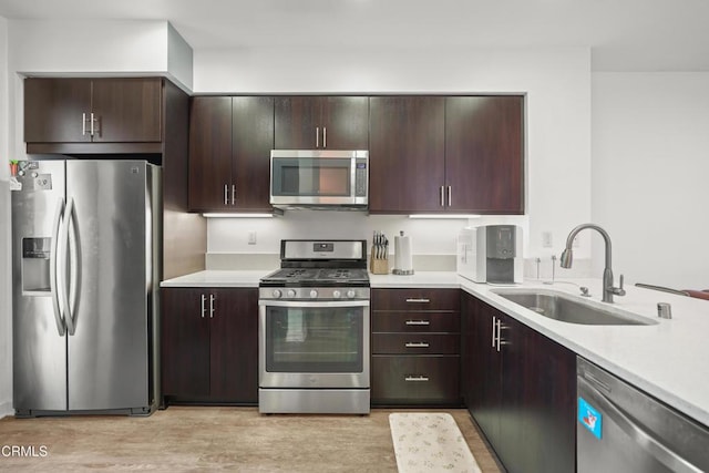 kitchen featuring light wood-style flooring, appliances with stainless steel finishes, light countertops, and a sink