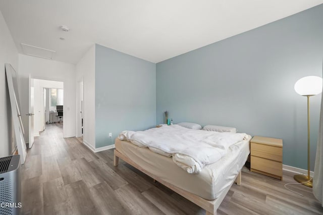 bedroom with attic access, baseboards, and wood finished floors