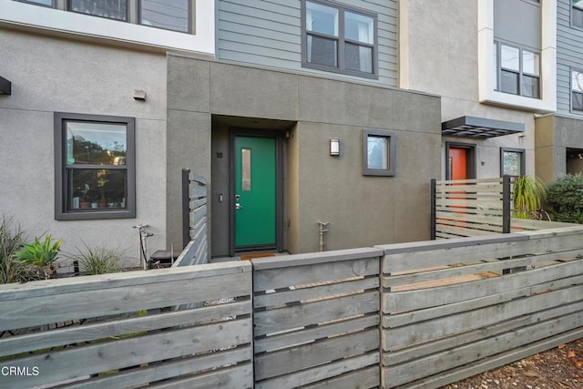 doorway to property with fence and stucco siding