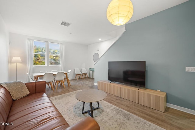 living room with recessed lighting, visible vents, baseboards, and wood finished floors