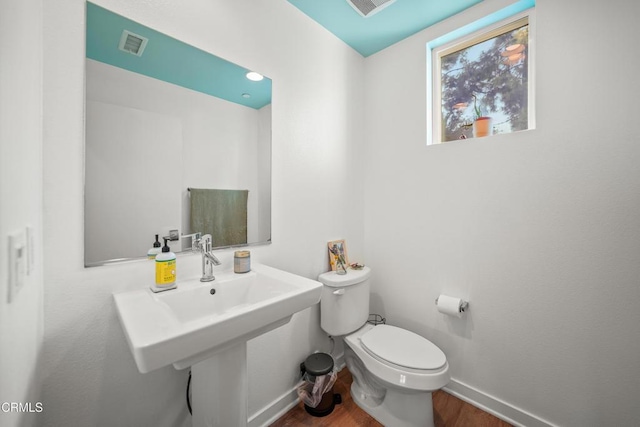 bathroom with toilet, baseboards, visible vents, and wood finished floors