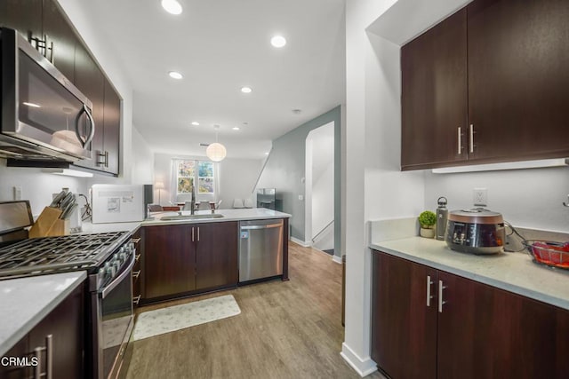 kitchen with stainless steel appliances, light wood-style floors, pendant lighting, a sink, and recessed lighting