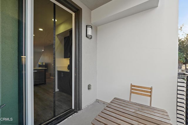 property entrance featuring a balcony and stucco siding