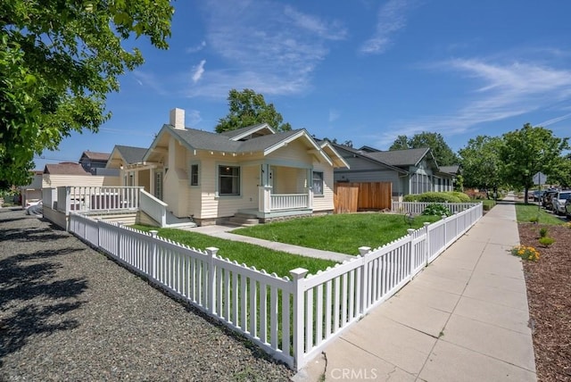 view of front facade featuring a fenced front yard, a chimney, a residential view, covered porch, and a front yard