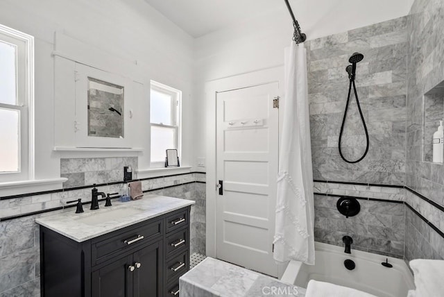 full bathroom with tile walls, shower / bathtub combination with curtain, and vanity