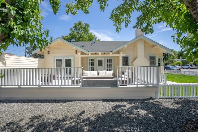 rear view of property with a chimney, fence, a deck, french doors, and outdoor lounge area