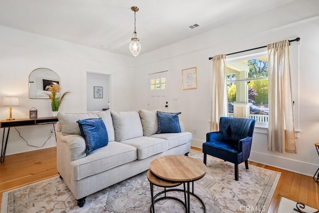 living room featuring hardwood / wood-style flooring, visible vents, and baseboards