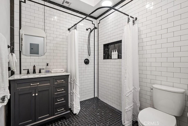 bathroom featuring toilet, visible vents, tile walls, and tiled shower