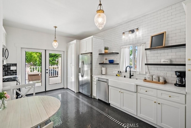 kitchen with appliances with stainless steel finishes, light countertops, white cabinetry, open shelves, and a sink