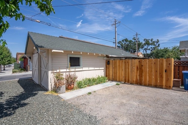 view of property exterior with roof with shingles and fence
