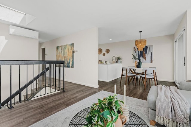 living room featuring a wall mounted AC, a skylight, dark wood finished floors, and baseboards