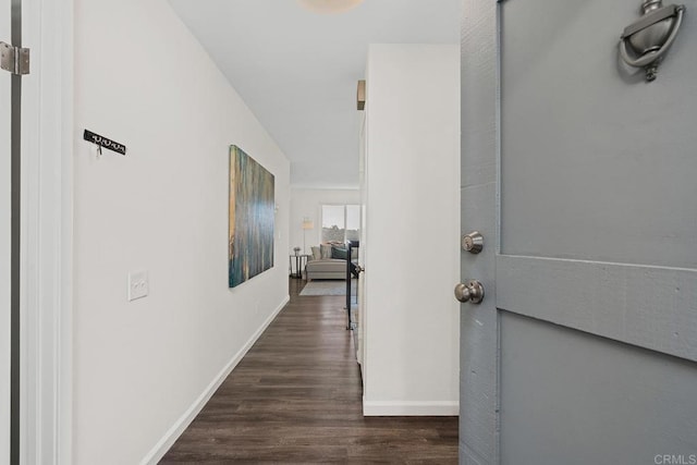 hallway featuring dark wood finished floors and baseboards