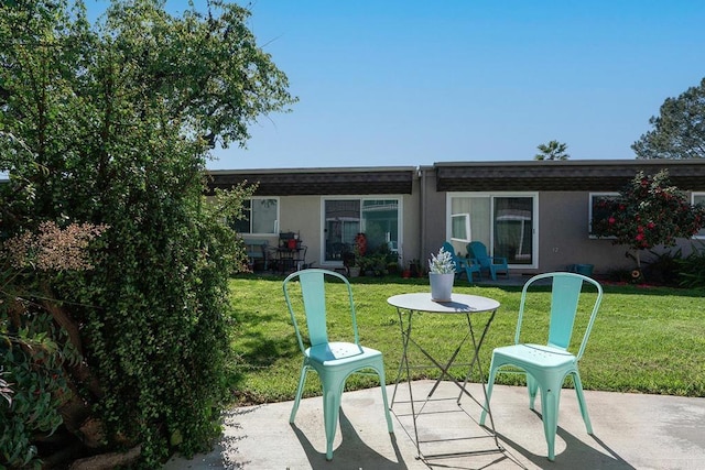 back of property with a patio, a lawn, and stucco siding