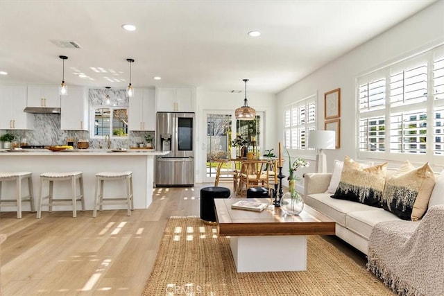 living room with light wood-type flooring, visible vents, and recessed lighting