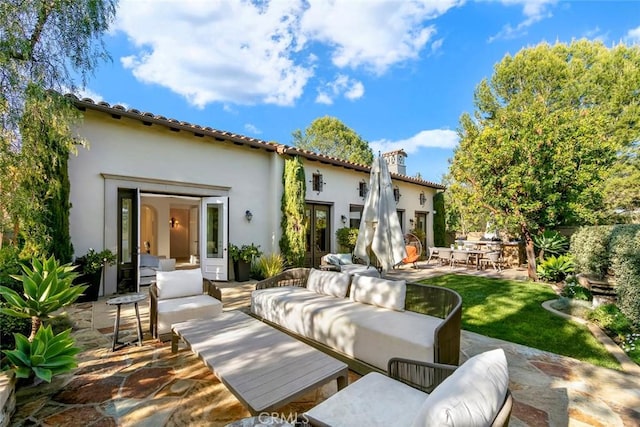 back of property with a patio, a chimney, an outdoor living space, and stucco siding