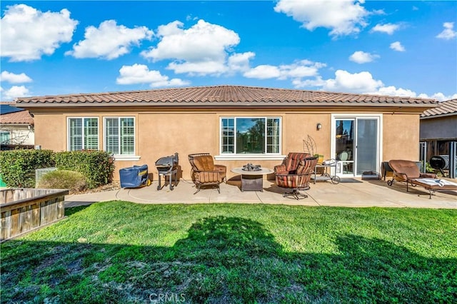 rear view of house with a tiled roof, a patio, a lawn, and stucco siding