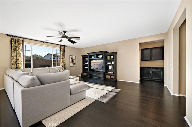 living room with ceiling fan, baseboards, and dark wood finished floors