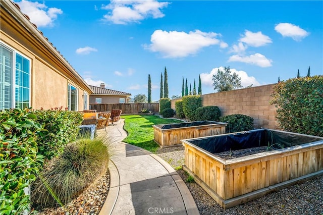 view of yard featuring a patio area, a fenced backyard, and a garden